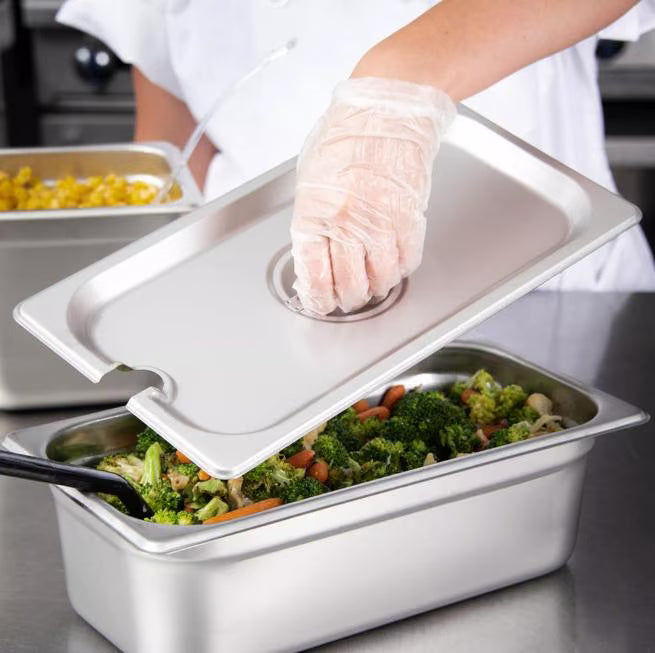 Protect and serve food efficiently with the DuraPan Stainless Steel Hotel Pan Slotted Handled Cover 1/3 Size 607130CS. Features heavy gauge stainless steel, a serving spoon notch, and a comfortable concave handle.